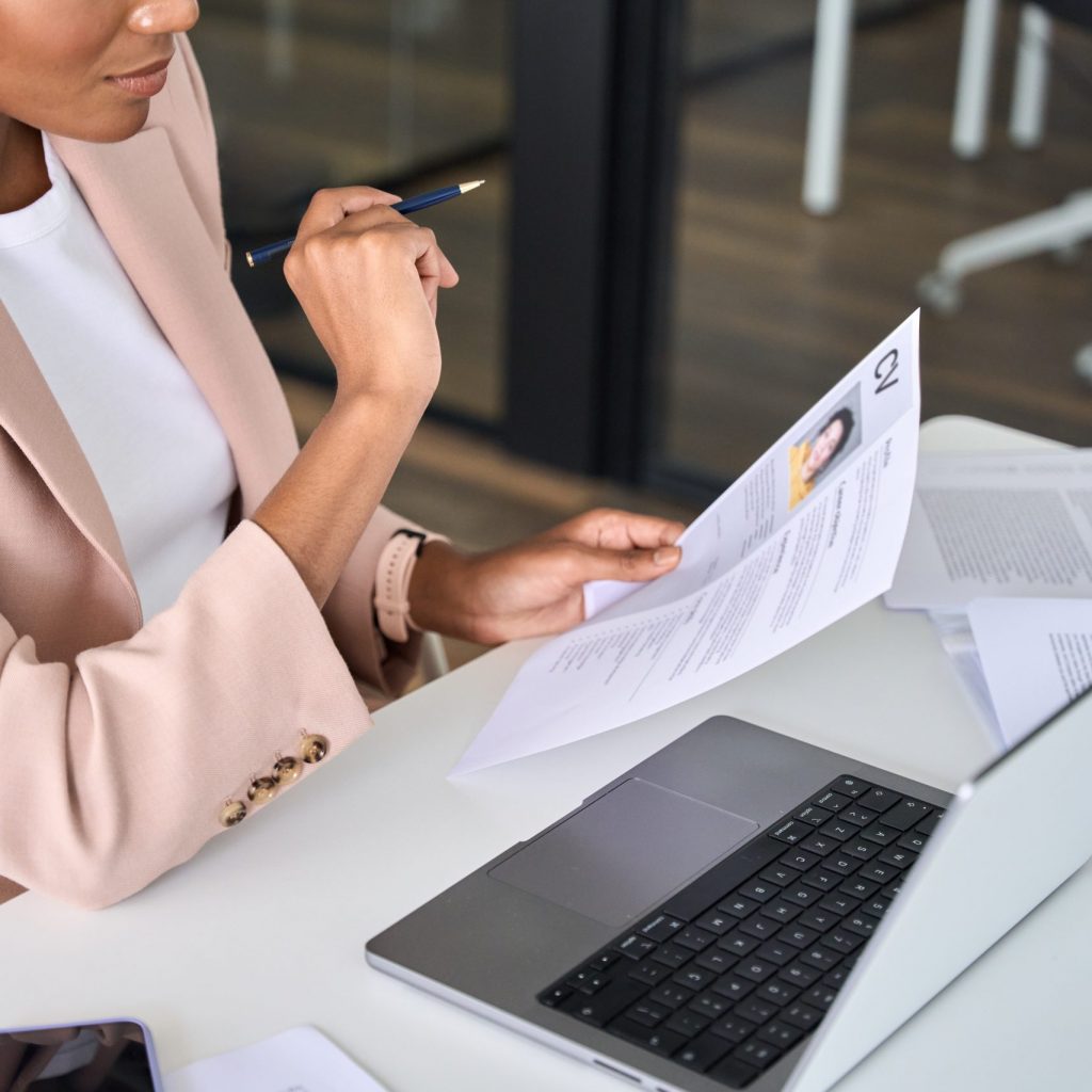 Close up view of female HR manager reading cv during virtual remote online job interview concept. Business woman employer holding resume hiring recruit in professional recruitment agency.